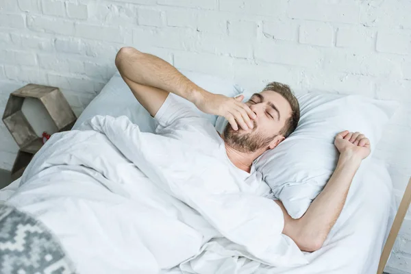 Schöner Junger Mann Gähnt Und Dehnt Sich Während Bett Liegt — Stockfoto
