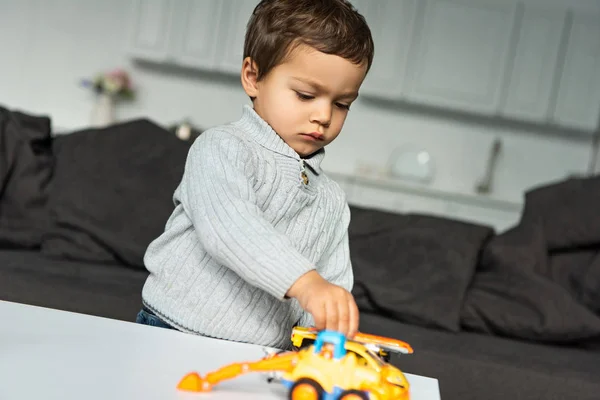 自宅のリビング ルームでおもちゃの車で遊ぶ少年  — 無料ストックフォト