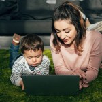 Mother and little son laying on floor with laptop at home