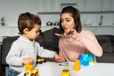 seçici odak yakınındaki küçük oğlu evde oyuncak uçak ile oynayan kadın