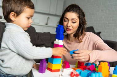 güzel kadın ve küçük oğlu renkli plastik blokları ile evde oynarken