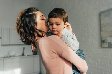 sevimli küçük oğlu evde ellerinde tutan anne yan görünüm