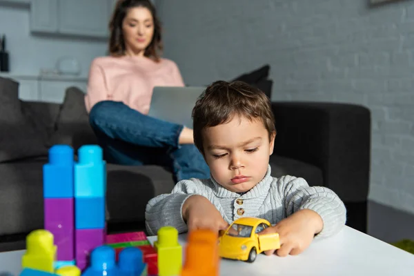 Enfoque Selectivo Niño Jugando Con Coche Juguete Mientras Que Madre — Foto de stock gratis