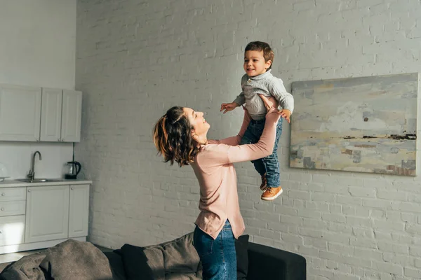 Vista Lateral Mujer Riendo Criando Pequeño Hijo Feliz Sala Estar —  Fotos de Stock