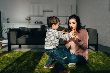 Anne ve küçük oğlu toy dinozorlar evde oturma odasında oynarken