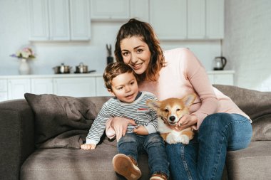 Anne ve küçük oğlu ile corgi köpek yavrusu evde kanepede oturan