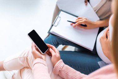 smartphone ve Doğum öncesi sınıf sırasında Pano'da yazma hamile kadınlar görünümünü kırpılmış