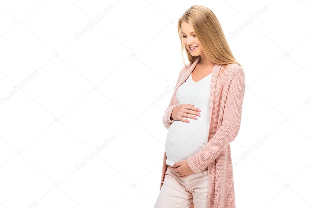 smiling pregnant woman touching belly and looking down isolated on white