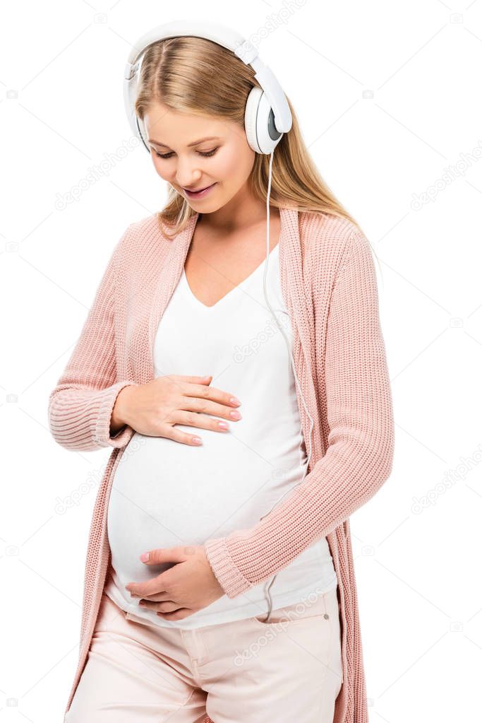 smiling pregnant woman touching belly and listening music isolated on white