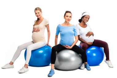 Üç mutlu hamile kadın fitness topları beyaz izole oturma