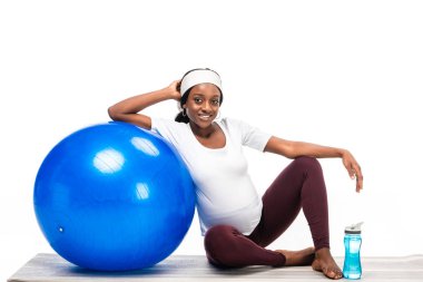 Afrikalı-Amerikalı kadın fitness topu üzerinde beyaz izole ile katta oturan