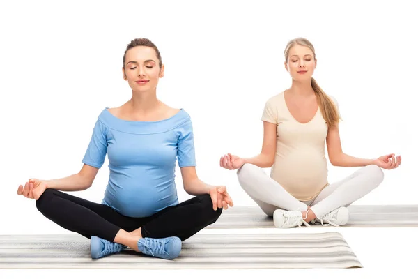 Duas Mulheres Grávidas Sentadas Chão Meditando Isoladas Branco — Fotografia de Stock