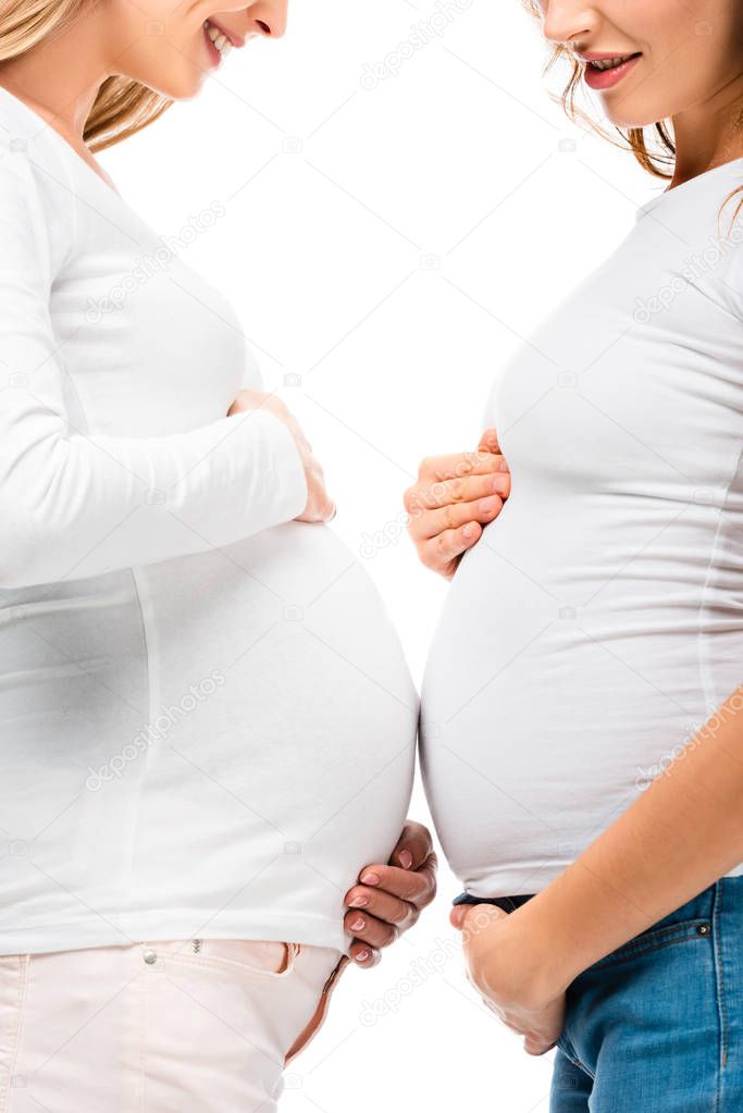 cropped view of smiling pregnant women standing close to each other isolated on white 