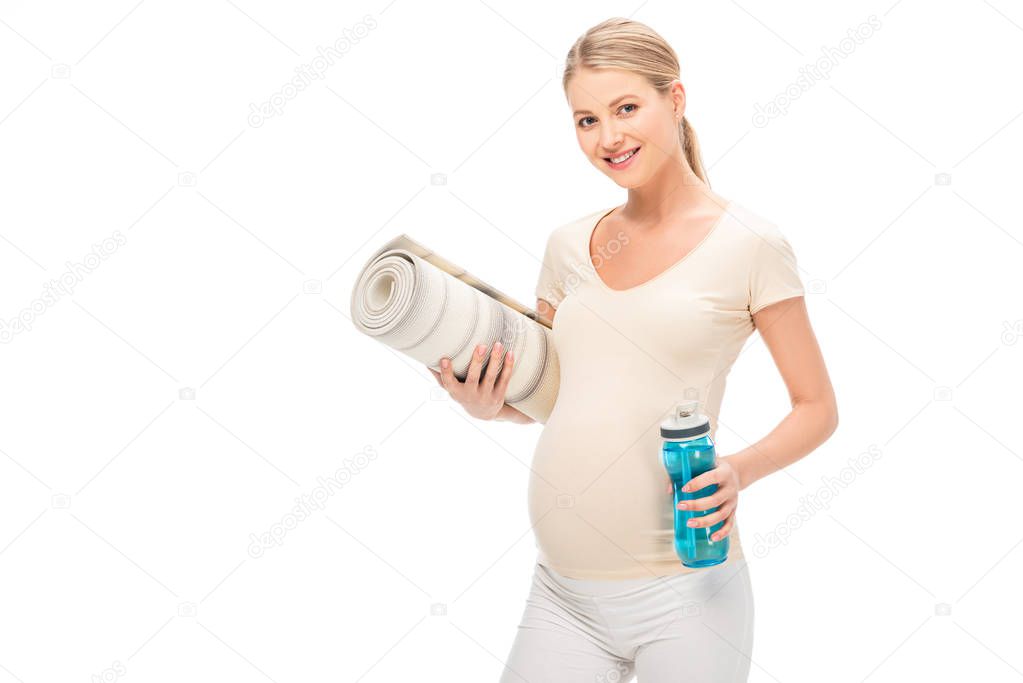 pregnant blonde woman holding fitness mat and bottle isolated on white