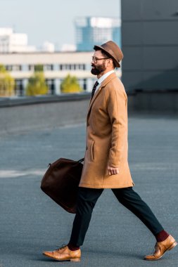 Çatıda yürümek çanta ile sakallı işadamı yan görünüm