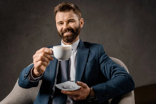 Fröhlicher Bärtiger Geschäftsmann Zeigt Tasse Kaffee — kostenloses Stockfoto