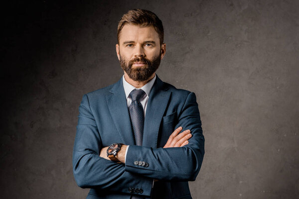 handsome bearded businessman standing with crossed arms 