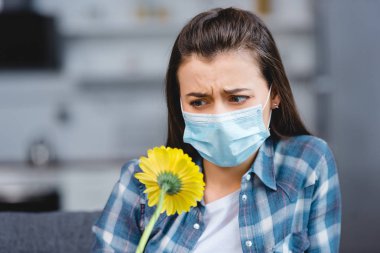 Tıbbi maske takıyor ve çiçeklere bakarak anti olan kadın 