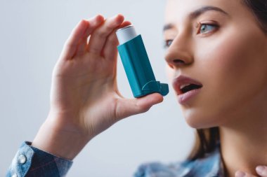 close-up view of young woman with asthma using inhaler clipart