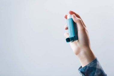 close-up partial view of young woman holding inhaler isolated on grey clipart