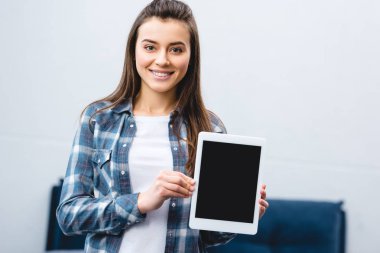 Dijital tablet boş ekran ile tutarak ve kameraya gülümseyen mutlu kız 