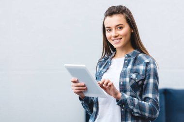 Dijital tablet kullanma ve kameraya gülümseyen mutlu genç kadın