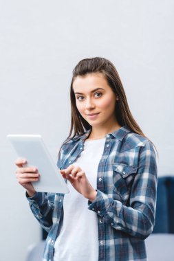 Dijital tablet kullanma ve kameraya gülümseyen çekici kız