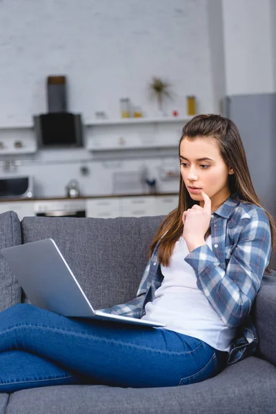 Jovem Mulher Pensativa Sentado Sofá Usando Laptop — Fotografia de Stock Grátis