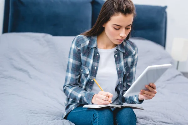 Mujer Joven Sosteniendo Tableta Digital Escritura Cuaderno Dormitorio — Foto de stock gratis