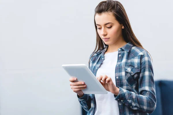 美丽的女孩在格子衬衫使用数字平板电脑在家里 — 图库照片