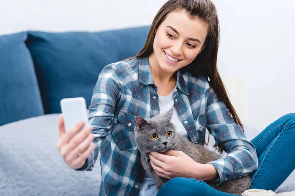 Ευτυχισμένη Γυναίκα Χρησιμοποιώντας Smartphone Και Λαμβάνοντας Αυτοπορτρέτα Χαριτωμένο Γκρι Γάτα — Δωρεάν Φωτογραφία