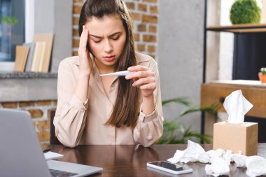Termometre tutarak ve office sıcaklık kontrol hasta genç iş kadını 