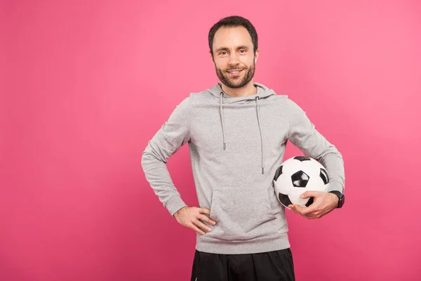 英俊的足球运动员拿着球孤立在粉红色 — 图库照片