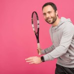 Спортивный красивый теннисист с ракеткой, изолированный на розовый