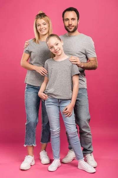 美丽的父母拥抱学龄前的女儿 孤立在粉红色 — 图库照片