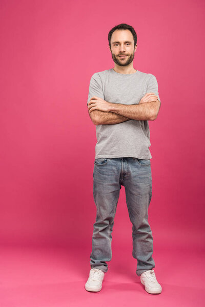 happy handsome man posing with crossed arms, on pink