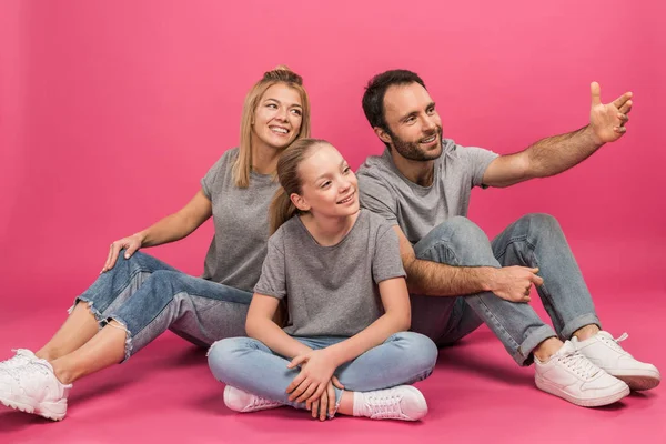 父が何かを見せながらピンクの上に座っての娘と幸せな家庭 — ストック写真