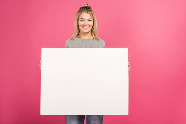 attractive woman holding empty board, isolated on pink