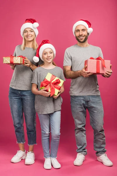 クリスマス ピンクのギフト ボックスを保持しているサンタ帽子で幸せな家族  — 無料ストックフォト
