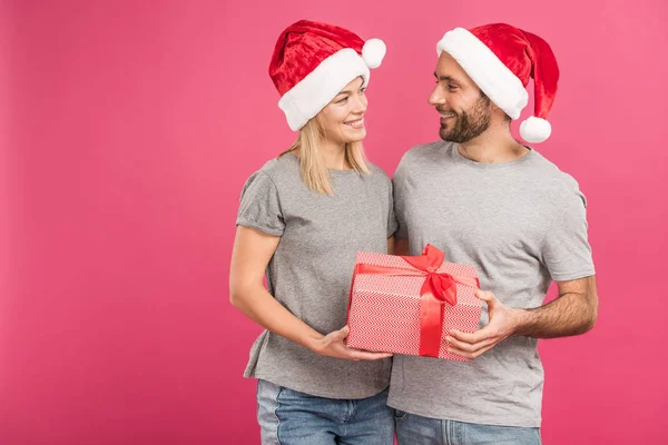 Happy Couple Santa Hats Hugging Holding Christmas Gift Box Isolated — Stock Photo, Image