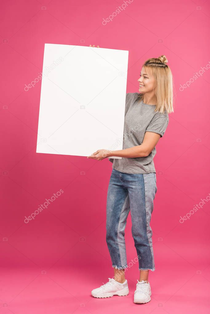 beautiful happy woman posing with empty placard, isolated on pink