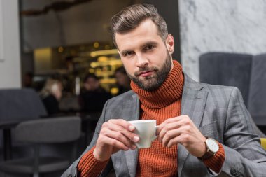 yakışıklı adam kameraya bakarak ve restoranda kahve içme formal giyim