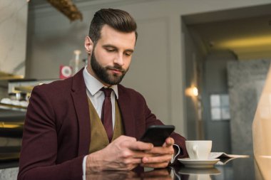yakışıklı işadamı ile kahve masada oturan ve restoranda smartphone kullanarak formal giyim