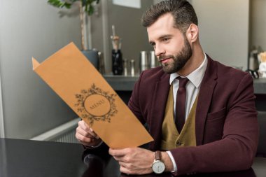 restoranda oturan ve menü tutarak formal giyim yakışıklı işadamı 