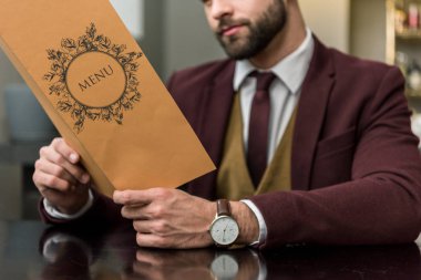 restoranda oturan ve menü tutarak formal giyim işadamı kırpılmış görünümünü 