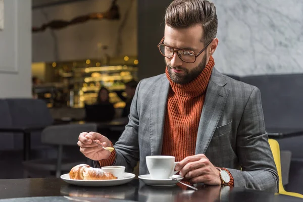 handsome man in formal wear and glasses sitting at table during lunch in restaurant