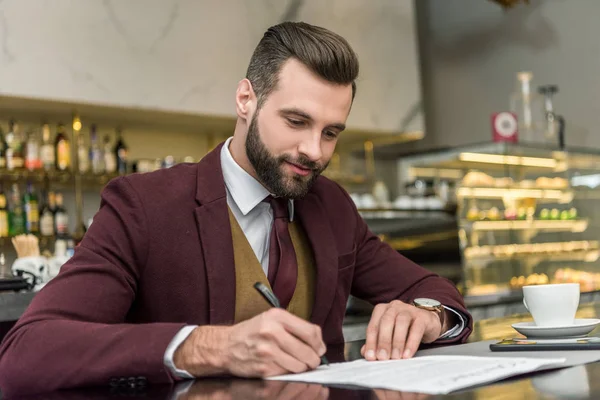 Schöner Geschäftsmann Formeller Kleidung Sitzt Bei Kaffee Tisch Und Unterschreibt — kostenloses Stockfoto