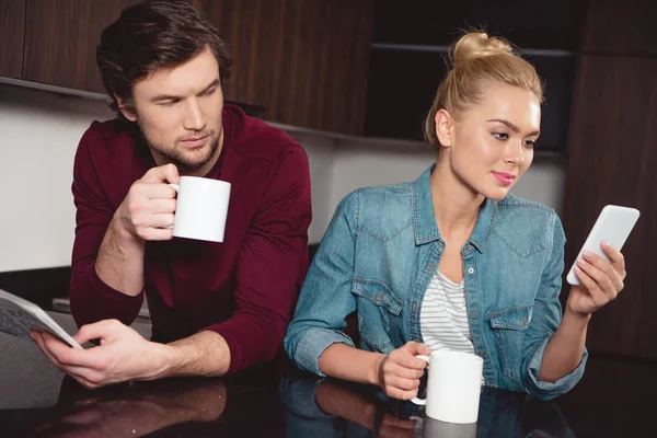 Jealous Husband Holding Coffee Cup Looking Wife Using Smartphone Kitchen — Stock Photo, Image