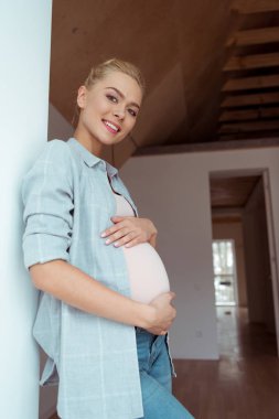 Karın her iki el ile dokunmak ve kamera dairede bakarak güzel hamile kız