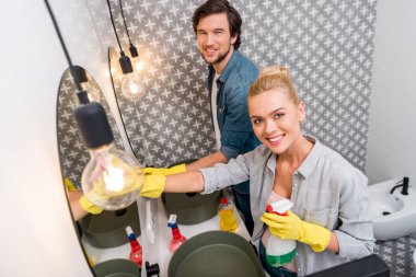 yakışıklı ve çekici kız olarak aynalar temizlik ve banyo kamerada bakarak lastik eldiven kız